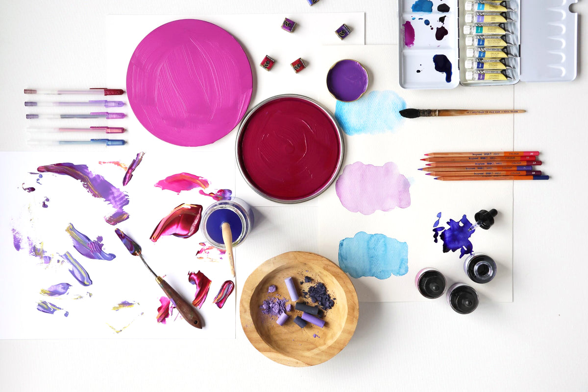 Art supplies including paint, brushes, and palettes on a white surface